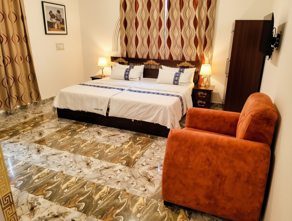 Habitación de hotel con cama, dos lámparas de noche, mesita de noche, una silla y piso estampado.