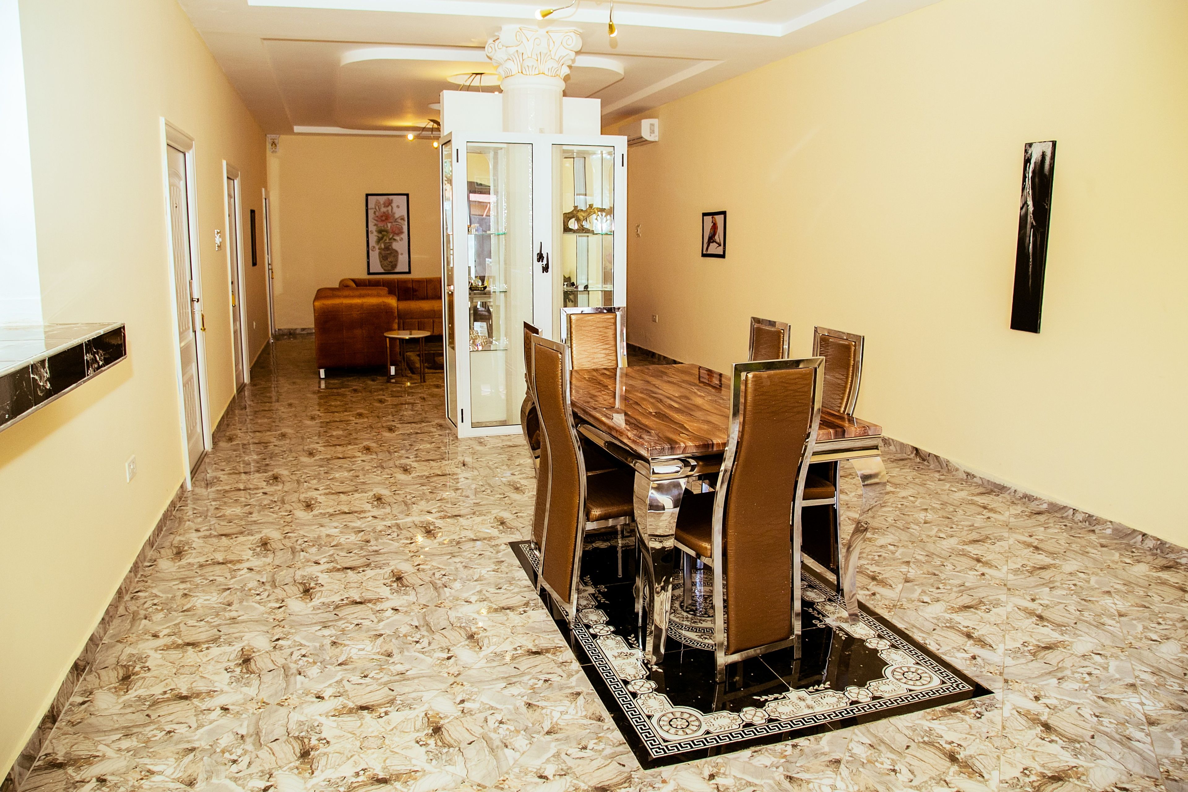 A dining area with a marble floor, a wooden dining table, and chairs.