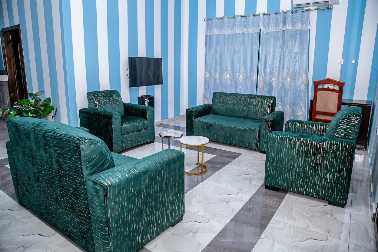 A living room with striped walls, a flat-screen TV, and green upholstered furniture.