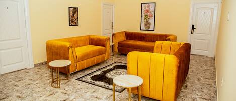 A living room with two yellow sofas, a round coffee table, and a patterned rug.