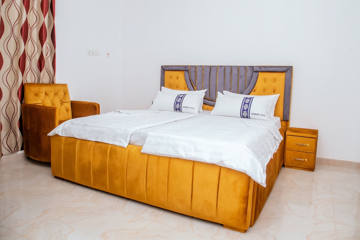 A bed with a headboard, two bedside tables, and a chair.