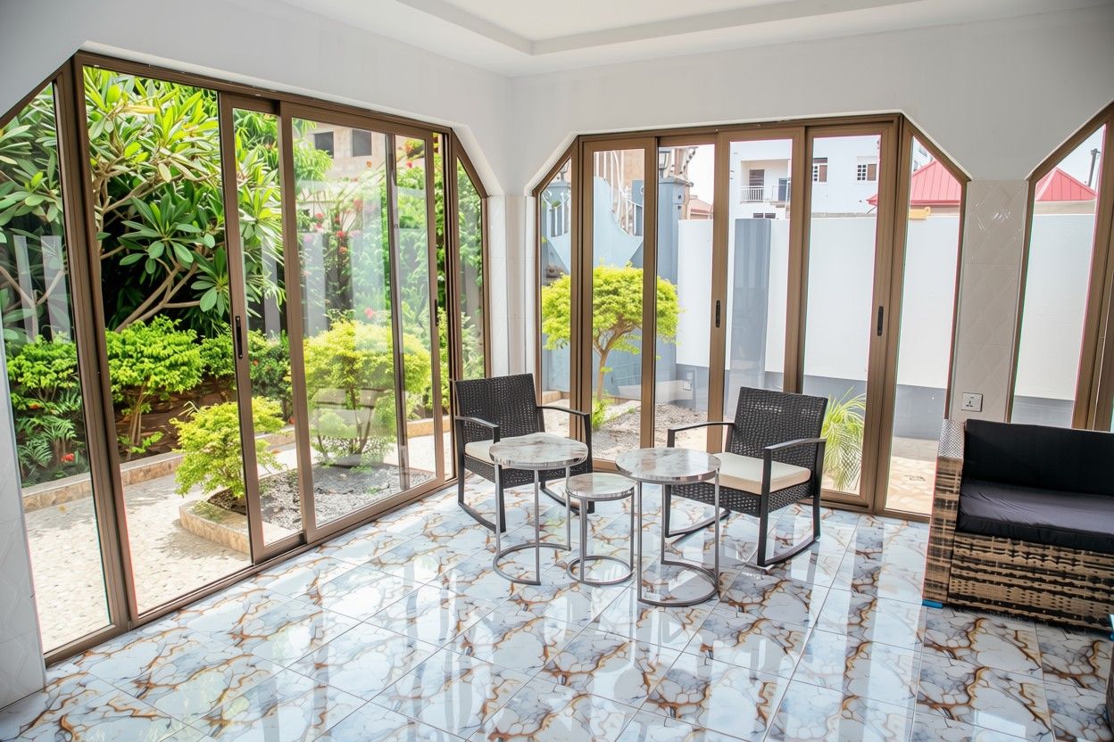 A spacious room with a glass partition, a tiled floor, and a seating area with a table and chairs.