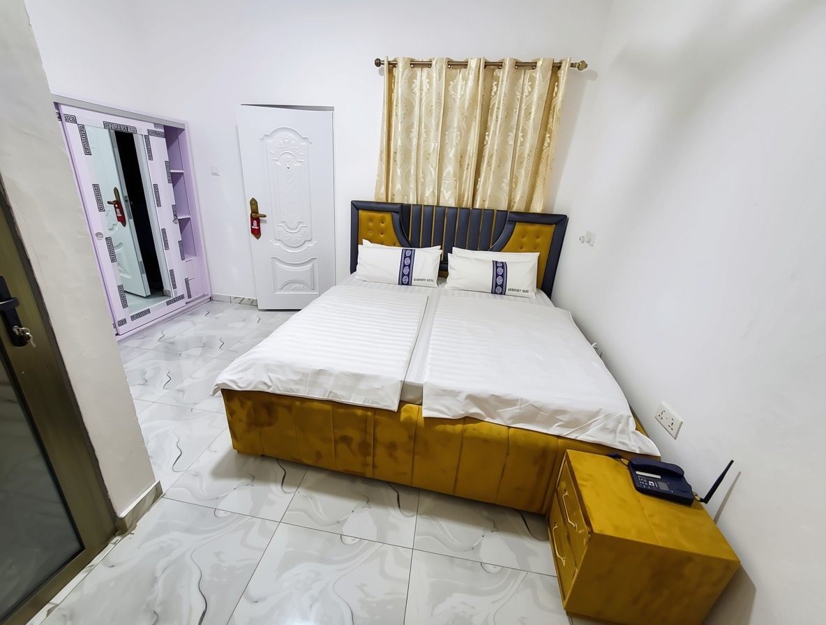 Una camera da letto con un letto, un armadio e un comodino con un telefono.