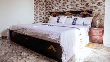 A bed with a dark headboard and gold accents, a bedside table with a lamp, and a patterned wall.