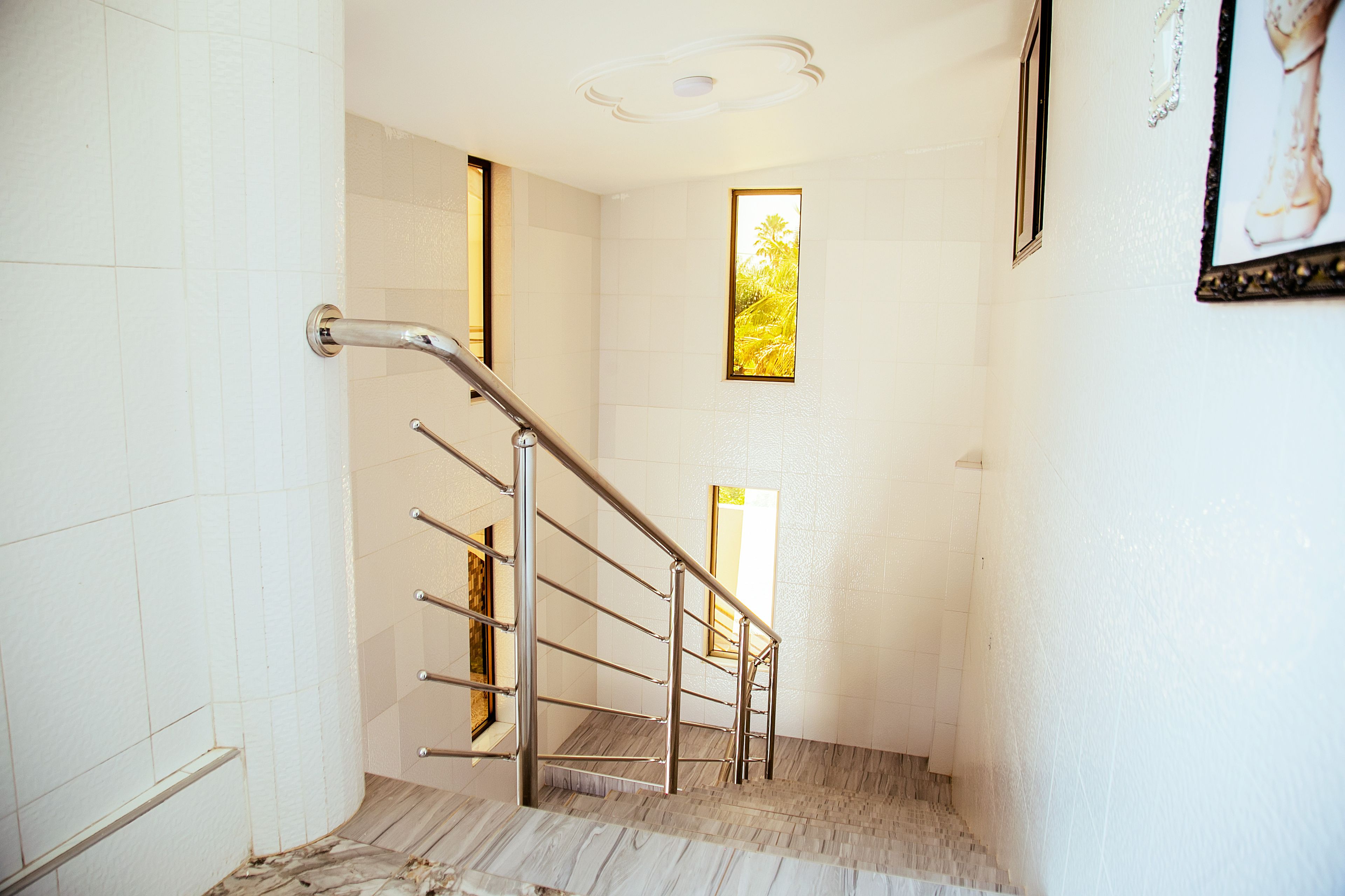 A staircase with metal handrails, white walls, and a wooden floor.