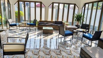Una habitación soleada con sofá, sillas, mesa, ventanas amplias y ventilador de techo.