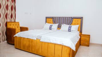 A bed with a headboard, two bedside tables, and a chair.