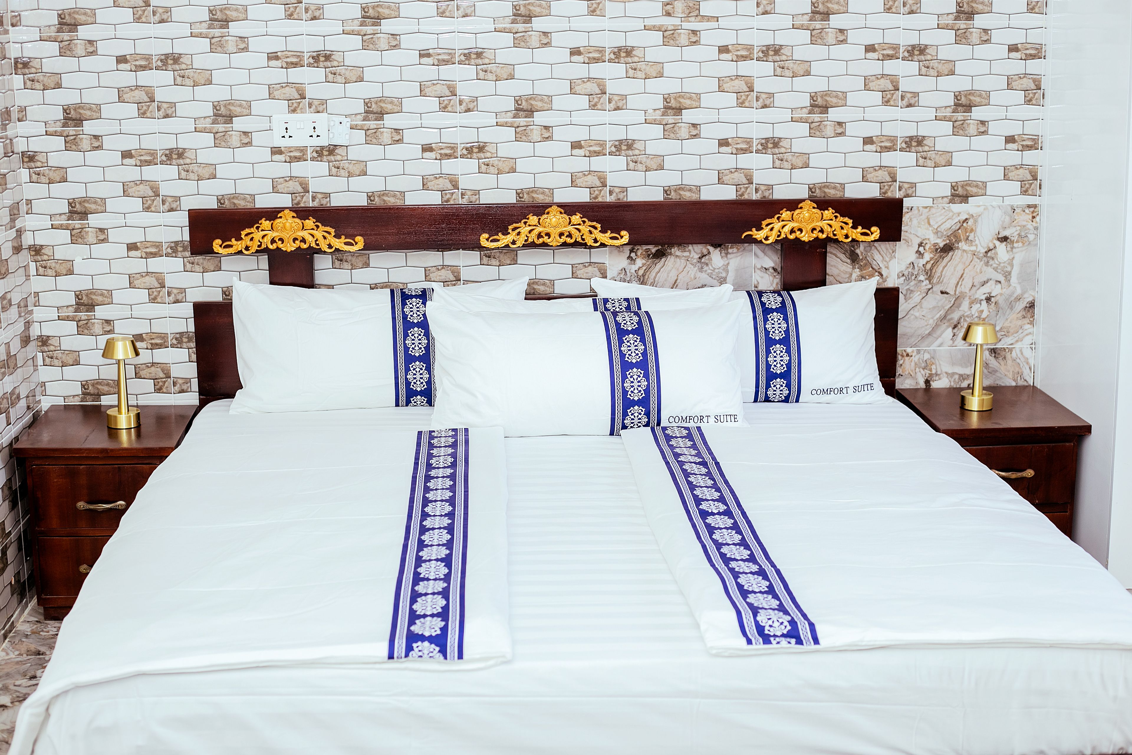 Une chambre d’hôtel avec un grand lit, deux tables de chevet et une tête de lit décorative.