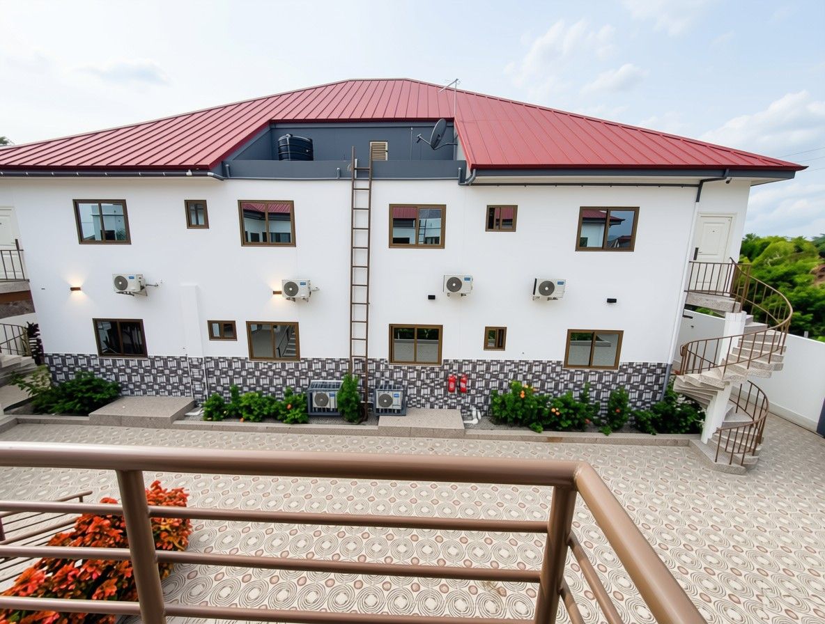 A two-story building with a red roof, multiple windows, and a staircase.