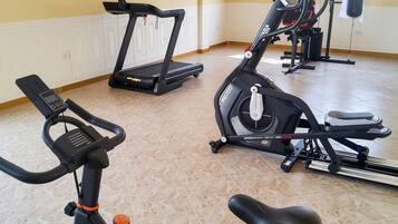 A gym with stationary bikes, a treadmill, and a punching bag.