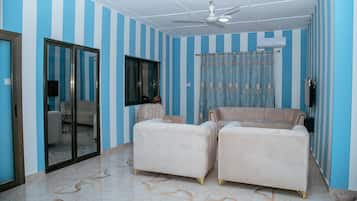 Una habitación con paredes a rayas, ventilador de techo, un sofá y una silla.