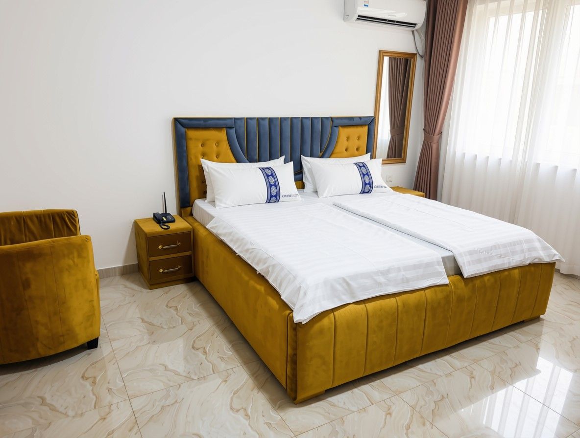 A double bed with a headboard, a bedside table, a lamp, and a trash bin.