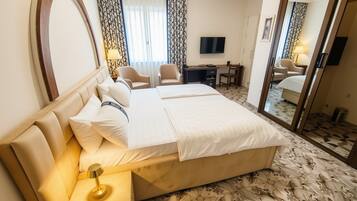 Une chambre d’hôtel avec un grand lit, un bureau avec une chaise, une télévision et un miroir.