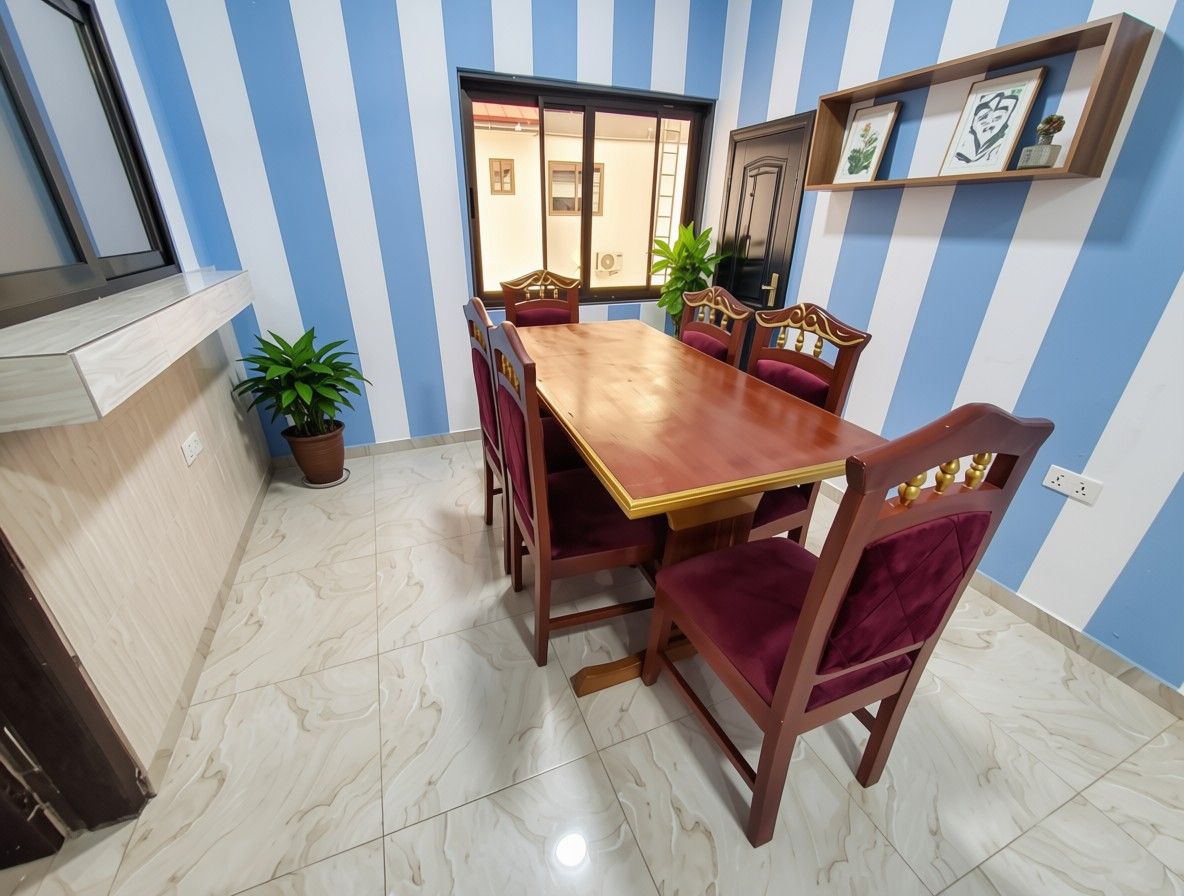 A dining area with a wooden table and chairs, a potted plant, and striped walls.