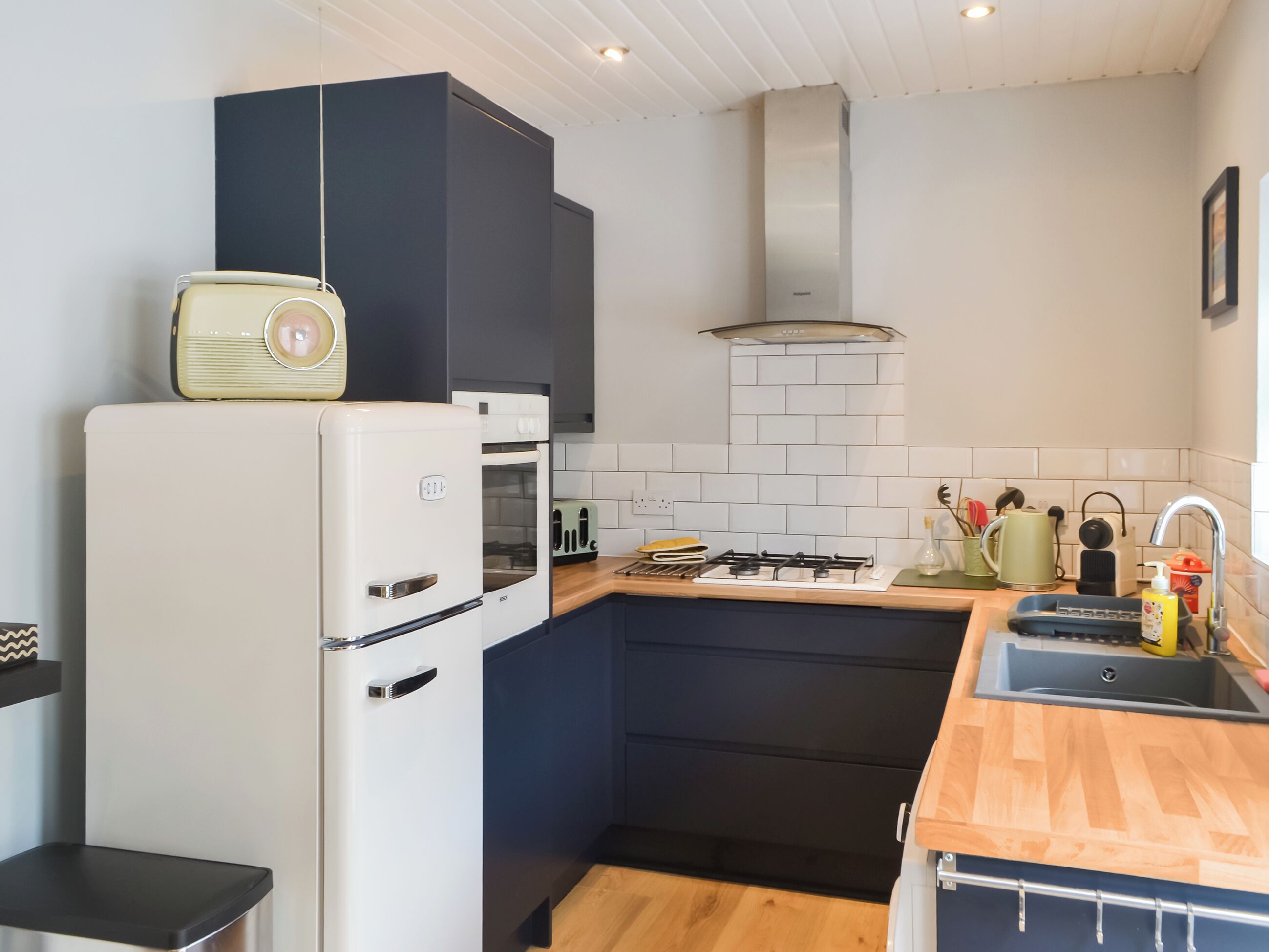 A compact kitchen with a white refrigerator, a built-in oven, a gas stove, and a wooden countertop.