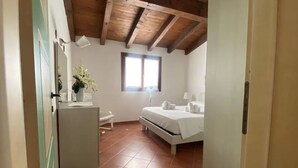 A bedroom with a bed, a bedside table, a small desk, a chair, a window, and a door. - Delightful sea View Apartment With Veranda (Stintino)