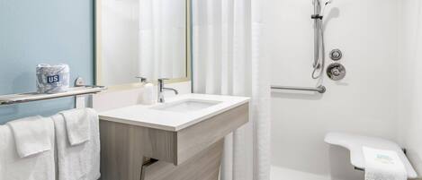 Ein modernes Badezimmer mit Waschbecken, Spiegel, Dusche und Handtuchhalter.