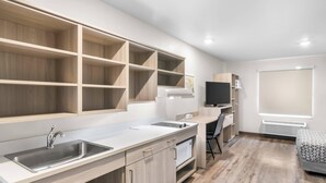 A modern kitchen with built-in shelves, a sink, and a microwave. - Woodspring Suites Elkhart (Elkhart)