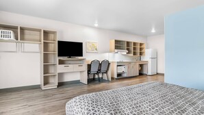 A modern room with a bed, a desk, a chair, a television, a kitchen area, and a wardrobe. - Woodspring Suites Elkhart (Elkhart)
