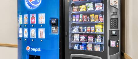 Máquina expendedora con el logotipo de Pepsi, que ofrece diversos snacks y bebidas.