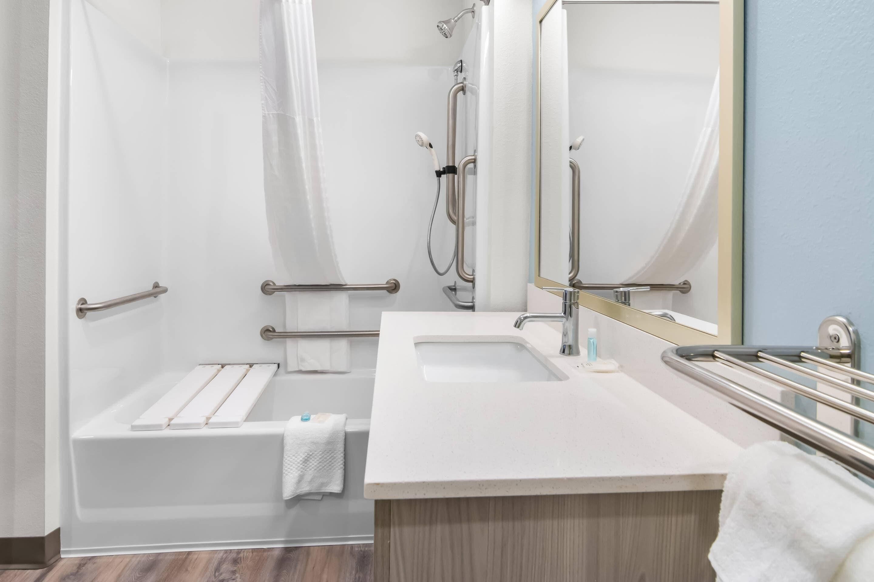 A modern bathroom with a shower, a sink, and a mirror.