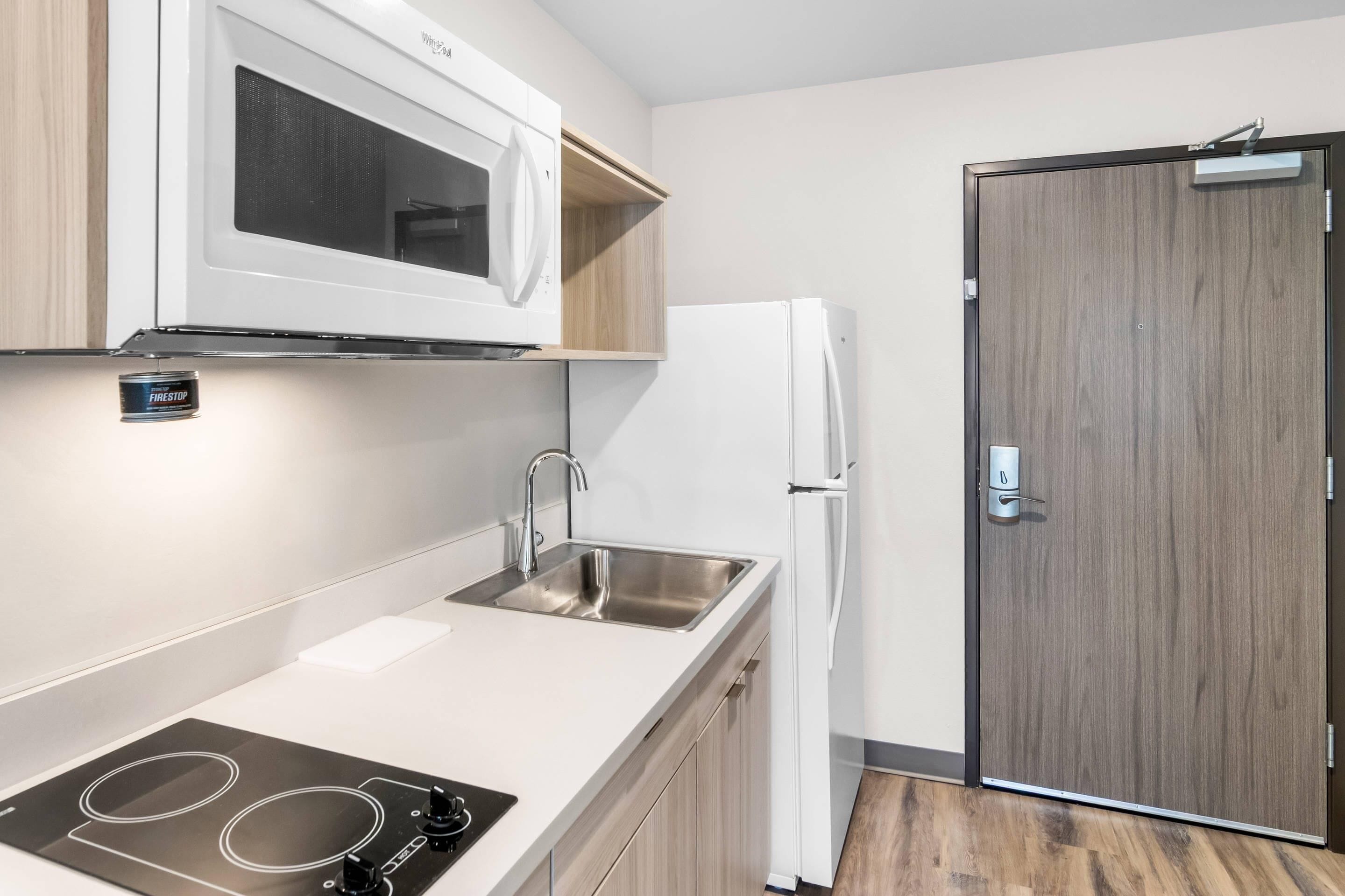 A modern kitchen with a built-in microwave, a stainless steel sink, and a white refrigerator.