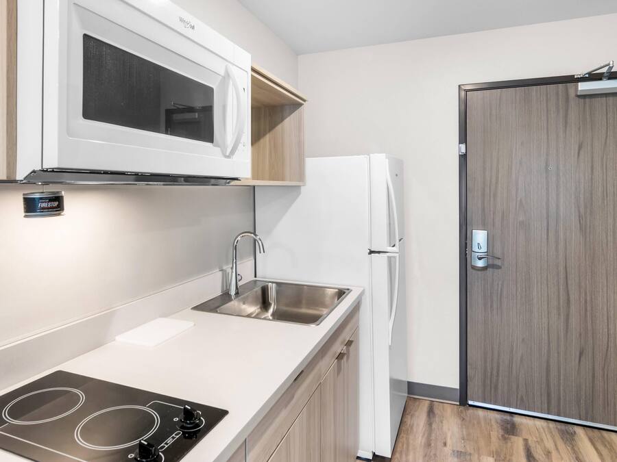 A modern kitchen with a built-in microwave, a stainless steel sink, and a white refrigerator.