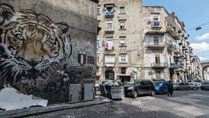 A building with a mural of a tiger, balconies with laundry, and parked cars. - Casa Luce del Sole - Two Bedroom Apartment, Sleeps 5 (Naples)
