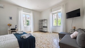 A bedroom with a bed, a sofa, a TV, a desk, and a window. - Casa Luce del Sole - Two Bedroom Apartment, Sleeps 5 (Naples)