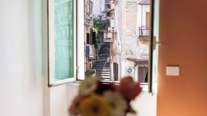 A narrow street view through a window with a flower arrangement on a table. - Casa Luce del Sole - Two Bedroom Apartment, Sleeps 5 (Naples)