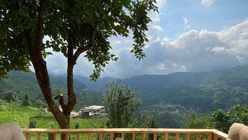 Relax in a serene outdoor seating area with a view of the lush valley and distant hills.