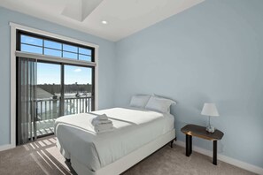 A bedroom with a bed, a nightstand, a lamp, and a large window with a view. - New Egg Harbor Construction with Pool,Hot Tub,Gym (Egg Harbor)