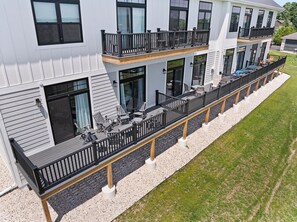 A multi-story building with a covered outdoor seating area, multiple balconies, and large windows. - New Egg Harbor Construction with Pool,Hot Tub,Gym (Egg Harbor)