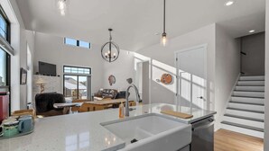Une cuisine moderne dotée d’un grand îlot central, d’un coin repas avec un canapé et des chaises, et d’un escalier menant à un autre niveau.