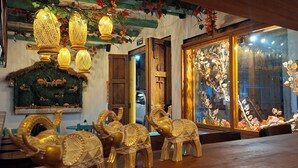 A restaurant interior with traditional decor, including hanging lanterns, wooden furniture, and a large window with autumn leaves. - San Miguel Villa Hotel's VDL (Villa de Leyva)
