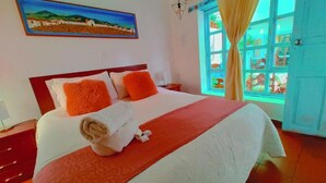 A hotel room with a large bed, a painting on the wall, and a window with curtains. - San Miguel Villa Hotel's VDL (Villa de Leyva)