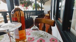 A table set with a bottle of liquor, a glass, and a decorative plate, under a covered outdoor area with a view of the street. - San Miguel Villa Hotel's VDL (Villa de Leyva)