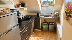 Cocina compacta con horno integrado, un lavamanos y ventana con vista a una zona residencial.