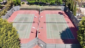 A tennis court with a net in the center, surrounded by a fence and trees. - 2-Bedroom Condo - close to all! (San Diego)