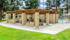 Enjoy dining and socializing under the shade of a pergola, surrounded by lush greenery and a sparkling pool.