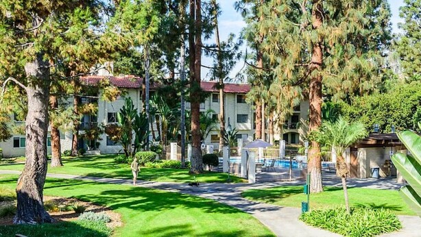 A hotel with a well-maintained lawn, tall trees, and a swimming pool area. - 2-Bedroom Condo - close to all! (San Diego)