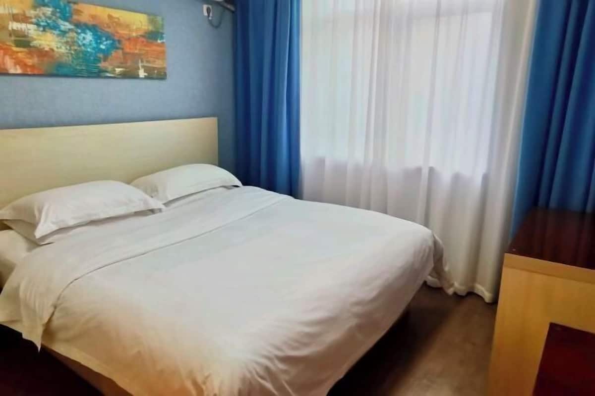 Cama bem arrumada com lençóis brancos, cabeceira e mesa de cabeceira de madeira.