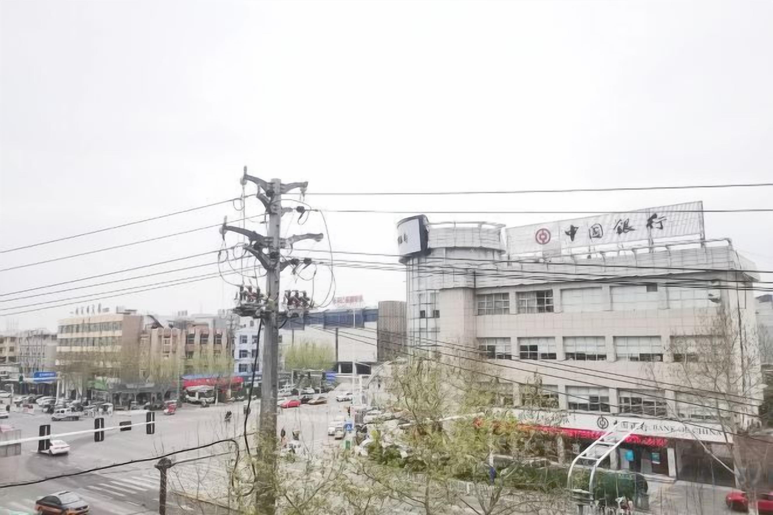 A multi-story building with a sign indicating a business or commercial use, surrounded by a busy street with vehicles and power lines.