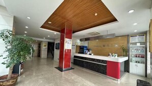 Un espace d’accueil doté d’un plafond en bois, d’un comptoir de réception, d’une plante en pot et d’un présentoir où sont exposés divers articles.