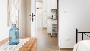 Un corridoio che porta a una cucina con un tavolo di legno e un vaso blu.