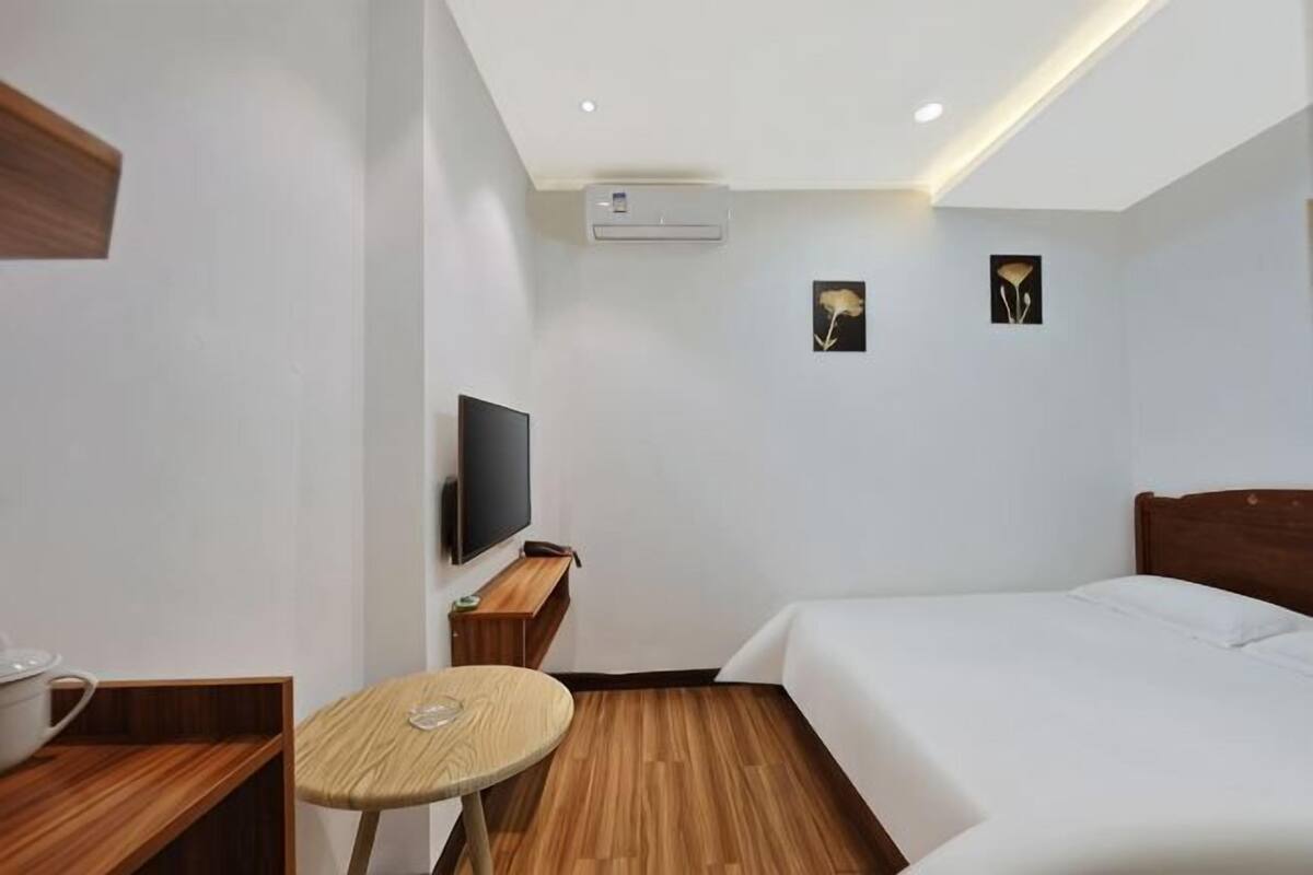 Habitación de hotel con una cama, televisor, una mesita redonda y aire acondicionado de pared.