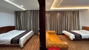 Een hotelkamer met twee bedden, een houten vloer en een groot raam met gordijnen.