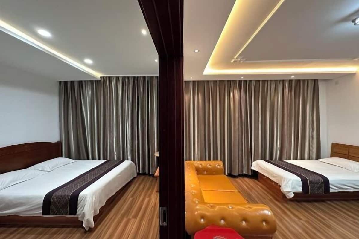 Habitación de hotel con dos camas, suelo de madera y un ventanal con cortinas.