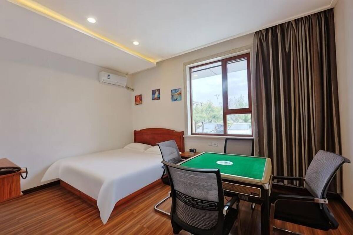 Una habitación de hotel con cama, mesa de billar y ventana con cortinas.