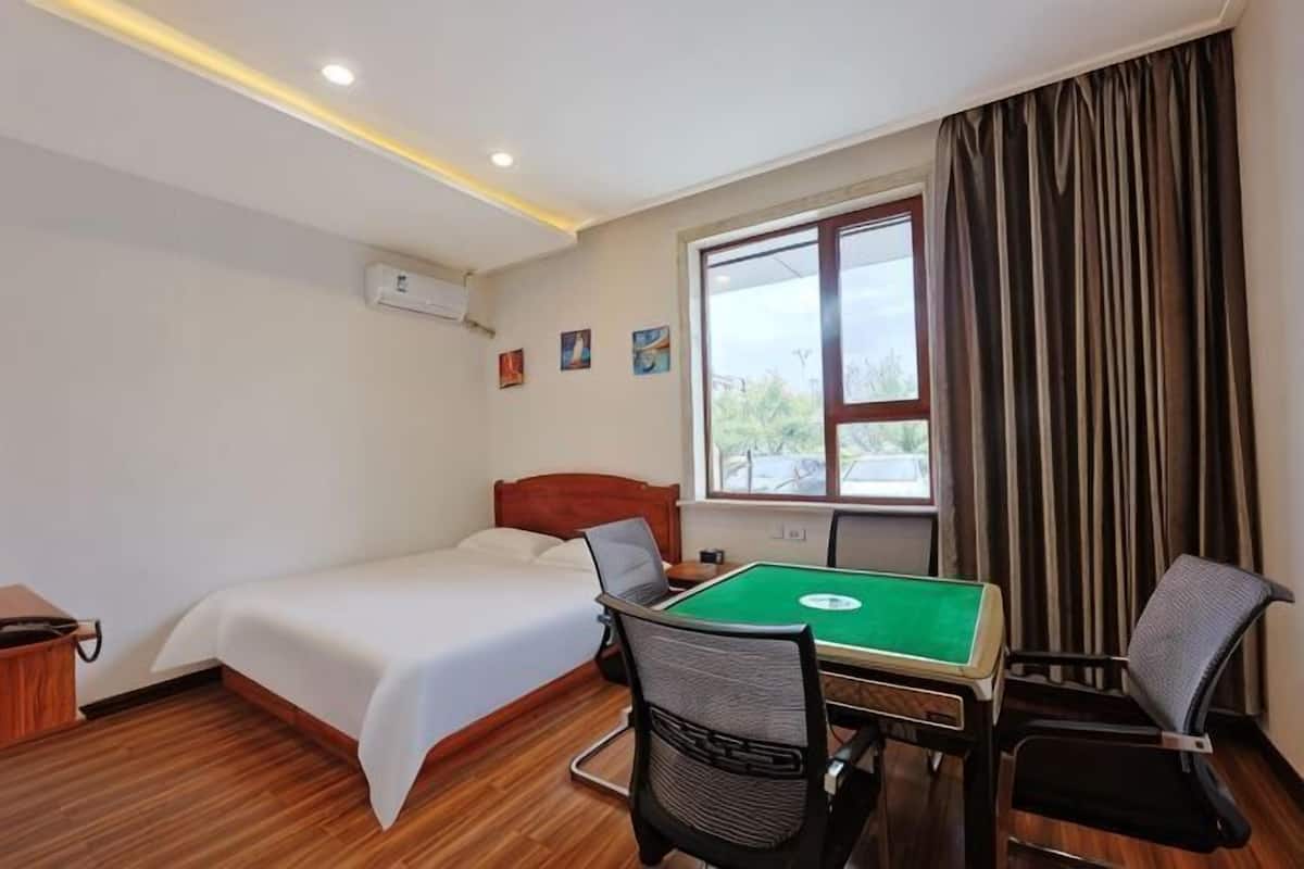 A hotel room with a bed, a pool table, and a window with curtains.